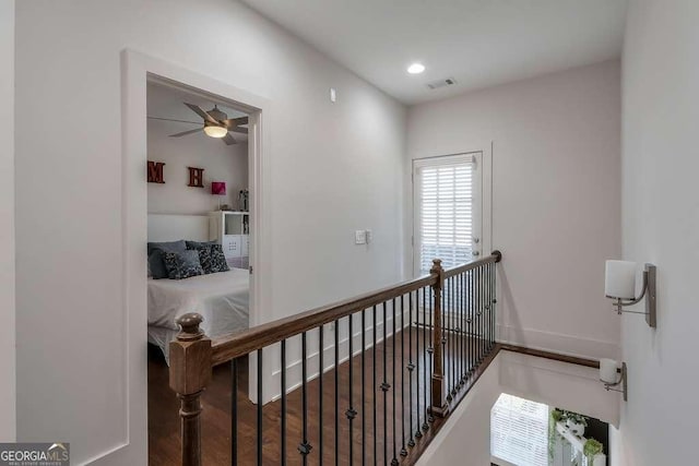 corridor with an upstairs landing, visible vents, baseboards, wood finished floors, and recessed lighting