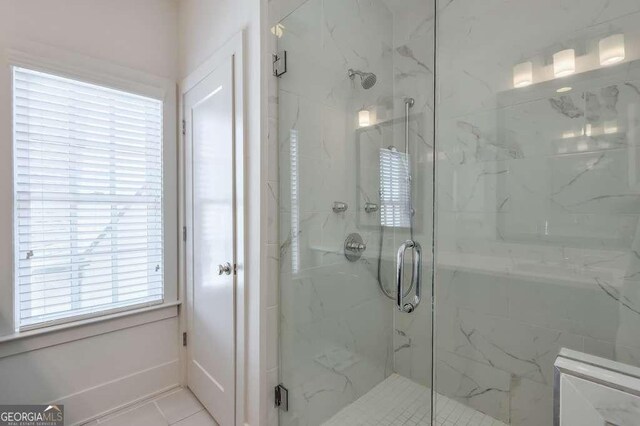full bath with tile patterned floors and a marble finish shower