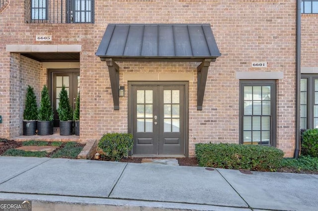 property entrance with brick siding, a standing seam roof, metal roof, and french doors