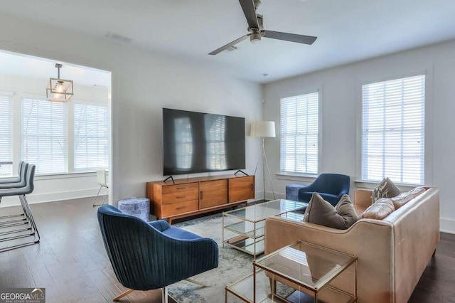 living area featuring a ceiling fan, visible vents, baseboards, and wood finished floors