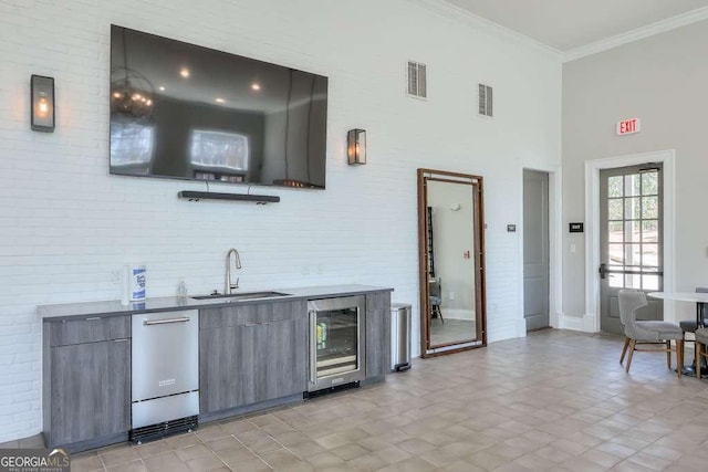 bar with crown molding, a sink, a high ceiling, beverage cooler, and visible vents