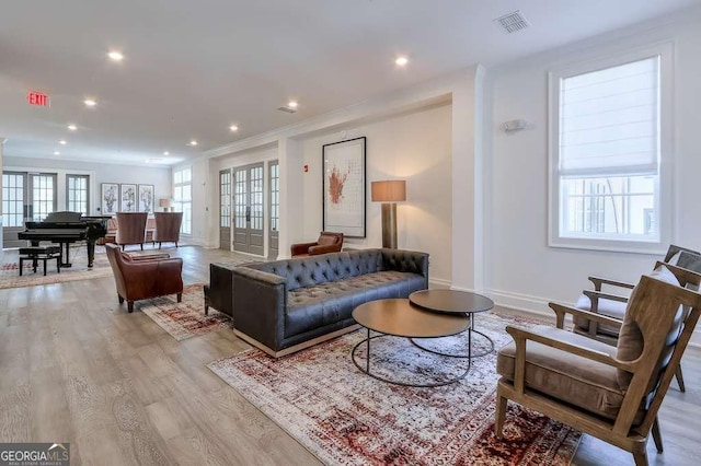 living area featuring baseboards, visible vents, light wood-type flooring, and plenty of natural light