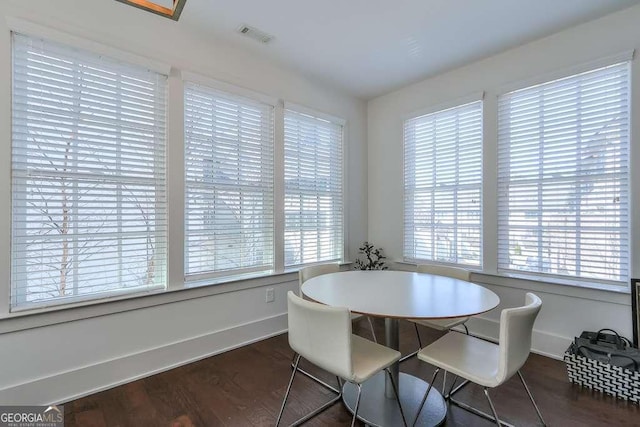 dining room with plenty of natural light, baseboards, visible vents, and wood finished floors