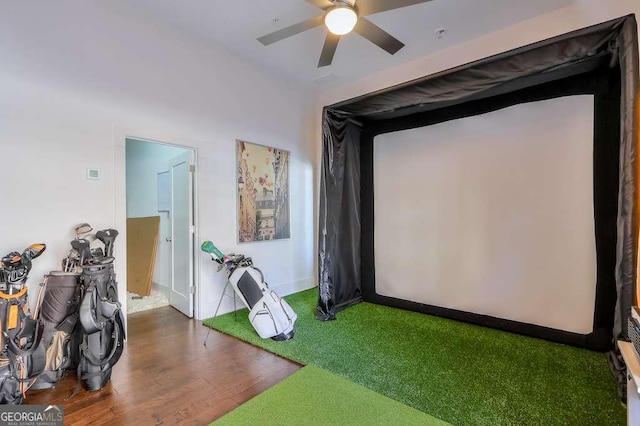 recreation room with wood finished floors, golf simulator, baseboards, and ceiling fan