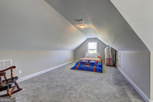 unfurnished bedroom with baseboards, visible vents, carpet, and vaulted ceiling