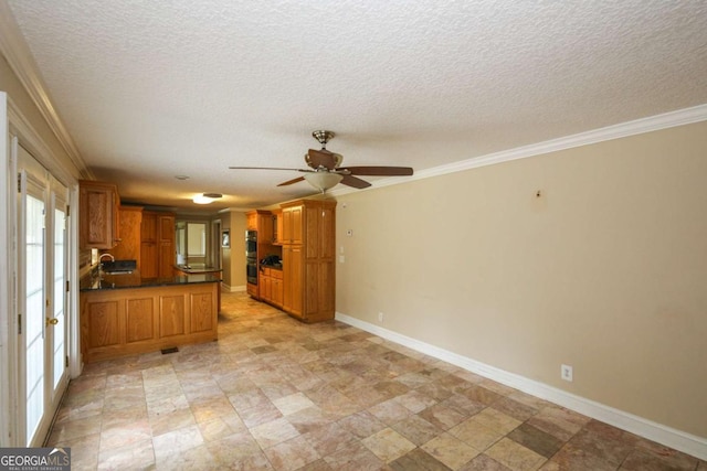 1100 Atlantic Ave, Waycross, GA 31501 - kitchen featuring ceiling fan, a peninsula, brown cabinetry, dark countertops, and a textured ceiling
