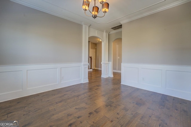 empty room featuring ornamental molding, a chandelier, visible vents, a decorative wall, and arched walkways
