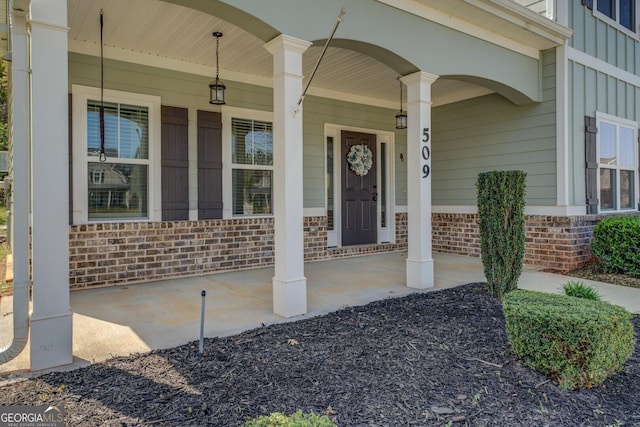 doorway to property with a porch and brick siding