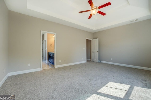unfurnished bedroom with visible vents, baseboards, a raised ceiling, and light colored carpet