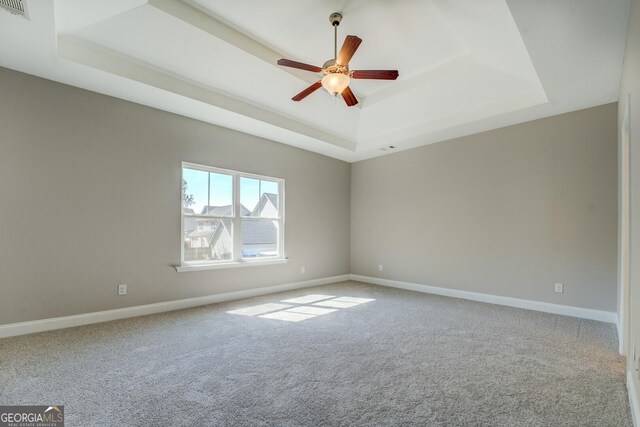 carpeted empty room with baseboards, a ceiling fan, and a raised ceiling