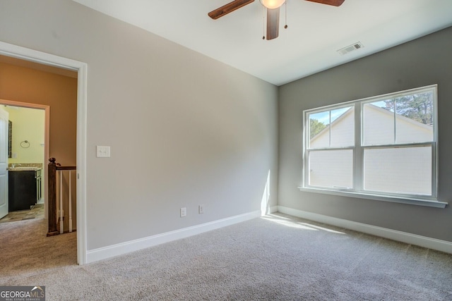 unfurnished room with light carpet, baseboards, a ceiling fan, and visible vents