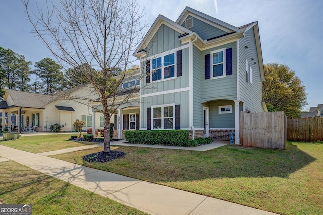 craftsman-style home featuring board and batten siding, fence, and a front lawn