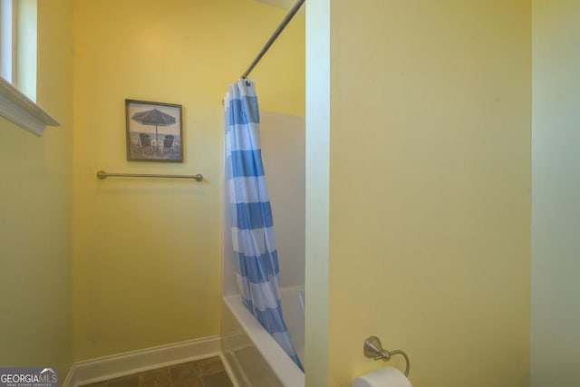 bathroom featuring shower / tub combo and baseboards