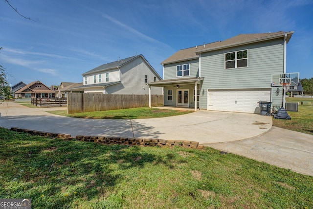back of house with a garage, fence, concrete driveway, and a lawn