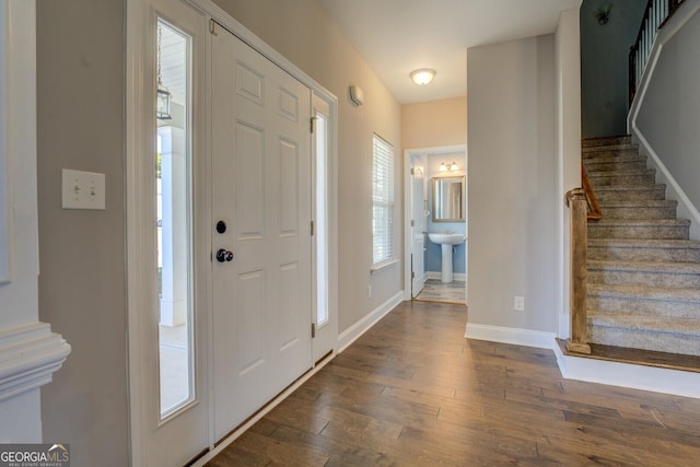 foyer with dark wood-style flooring, baseboards, and stairs