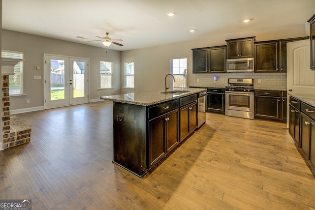 kitchen featuring tasteful backsplash, a sink, ceiling fan, appliances with stainless steel finishes, and light wood-style flooring
