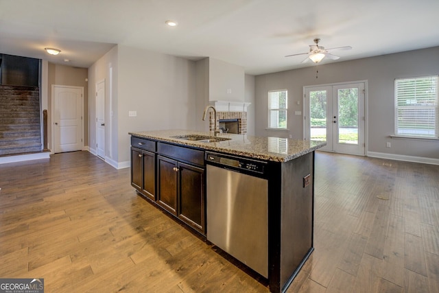 kitchen featuring open floor plan, a ceiling fan, a brick fireplace, dishwasher, and a sink