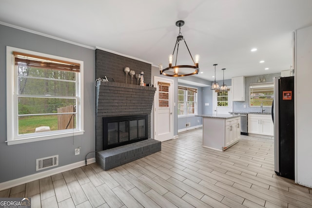 4329 Cedar Valley Ln, Conley, GA 30288 - kitchen featuring stainless steel appliances, a chandelier, white cabinetry, a brick fireplace, and a center island