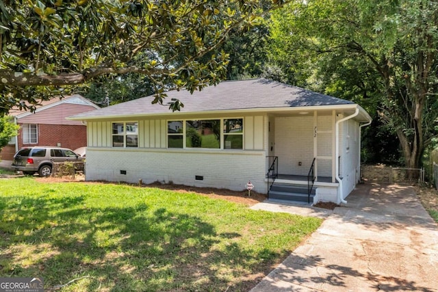 ranch-style home with concrete driveway, brick siding, board and batten siding, a front lawn, and crawl space