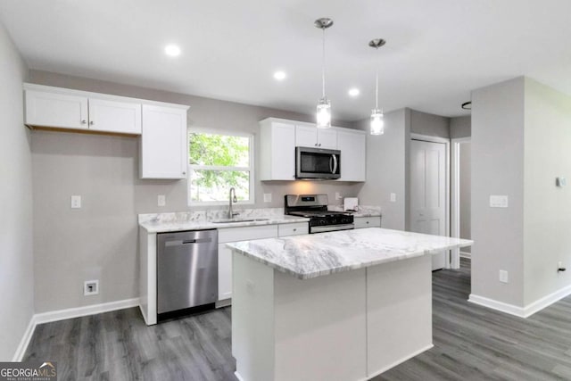 kitchen featuring white cabinets, a sink, a center island, and appliances with stainless steel finishes
