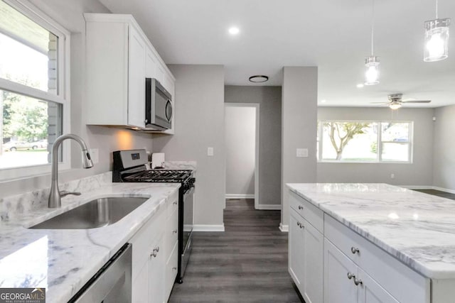 kitchen featuring light stone counters, a sink, appliances with stainless steel finishes, dark wood-style floors, and white cabinets