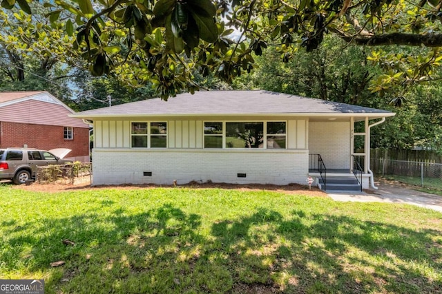 ranch-style house with board and batten siding, crawl space, fence, and a front lawn