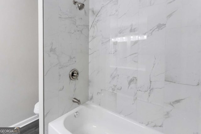 full bath featuring baseboards, bathtub / shower combination, and toilet