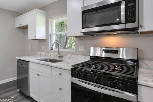 kitchen featuring a sink, white cabinetry, light stone counters, and appliances with stainless steel finishes