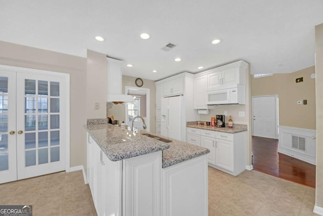 2983 Bancroft Gln NW, Kennesaw, GA 30144 - kitchen featuring white appliances, white cabinetry, french doors, light tile patterned floors, and wainscoting