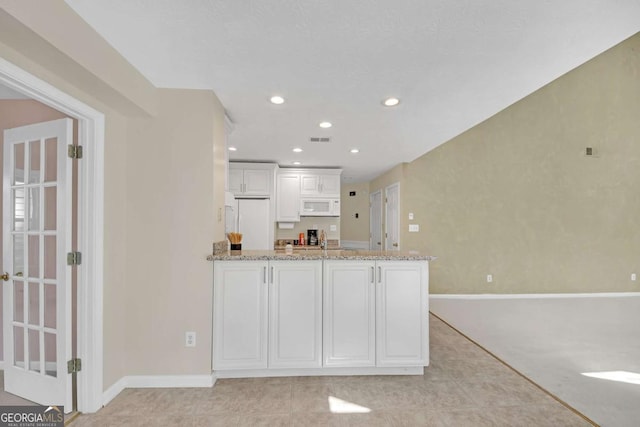 2983 Bancroft Gln NW, Kennesaw, GA 30144 - kitchen with white appliances, light stone counters, a peninsula, white cabinets, and recessed lighting