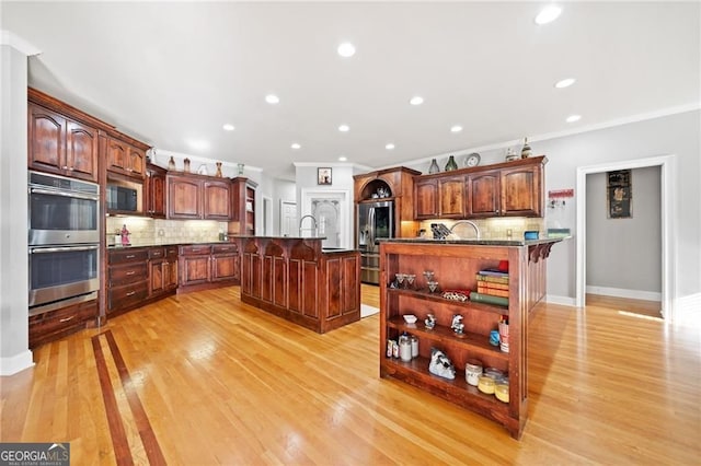 kitchen featuring stainless steel appliances, a kitchen breakfast bar, a kitchen island with sink, backsplash, and recessed lighting