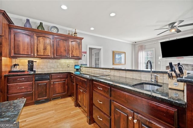 kitchen with a sink, ceiling fan, ornamental molding, dark stone countertops, and backsplash