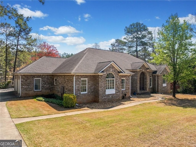 view of front facade featuring a front lawn, brick siding, roof with shingles, and asphalt driveway
