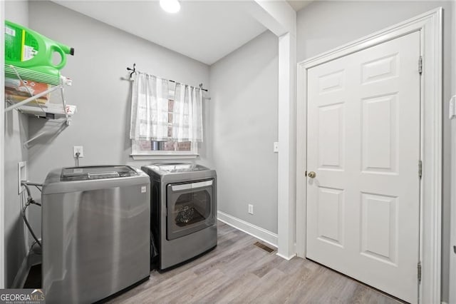 washroom featuring washing machine and clothes dryer, wood finished floors, and baseboards
