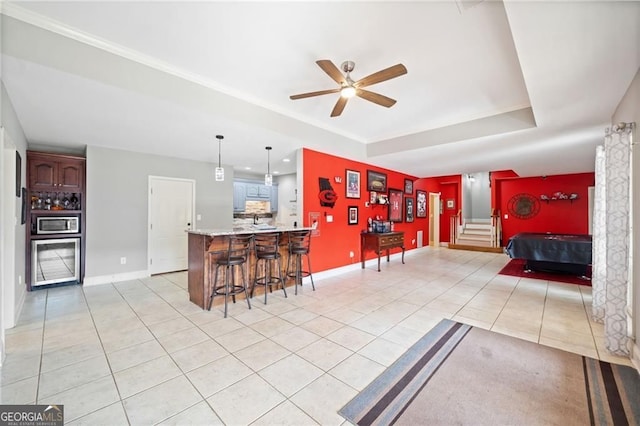 kitchen with light tile patterned flooring, a breakfast bar, ceiling fan, a peninsula, and stainless steel microwave