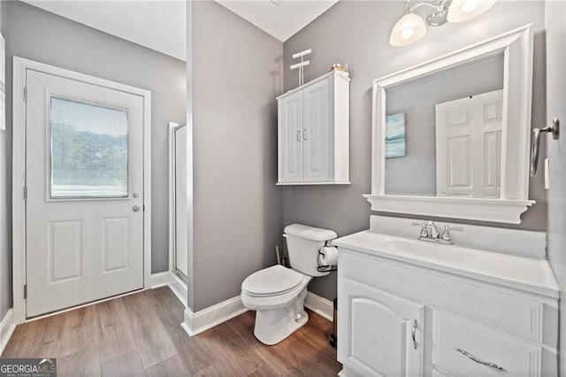 bathroom featuring baseboards, toilet, wood finished floors, vanity, and a shower stall