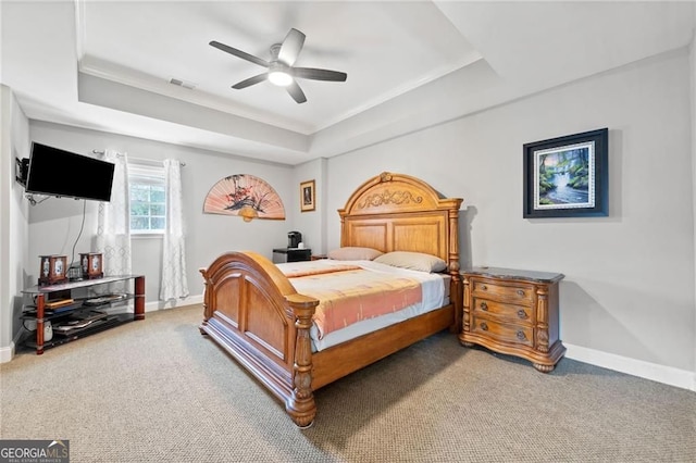 bedroom with a tray ceiling, light colored carpet, baseboards, and a ceiling fan