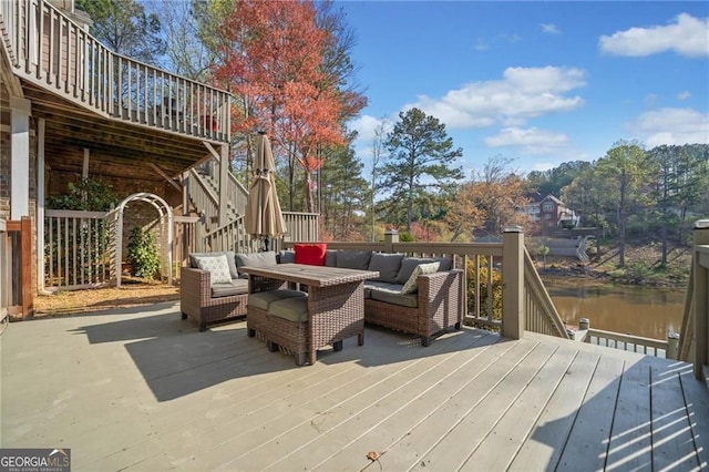 wooden deck with an outdoor hangout area, stairway, and a water view