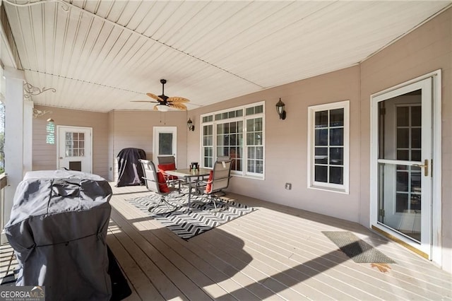 wooden deck with outdoor dining space and ceiling fan