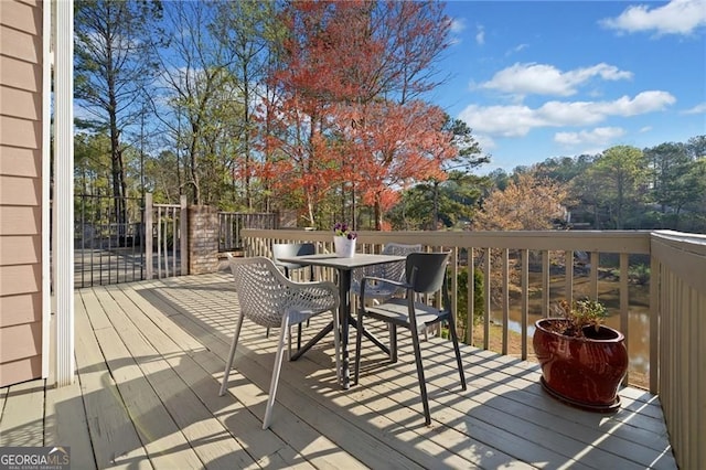 wooden terrace featuring outdoor dining space and view of scattered trees