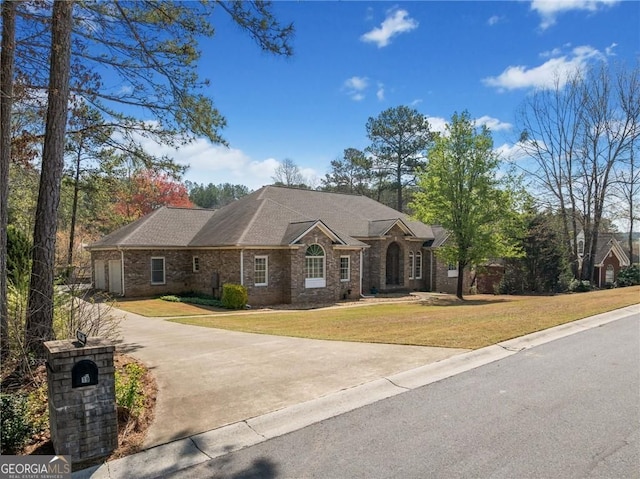view of front of home featuring a front lawn, concrete driveway, and brick siding
