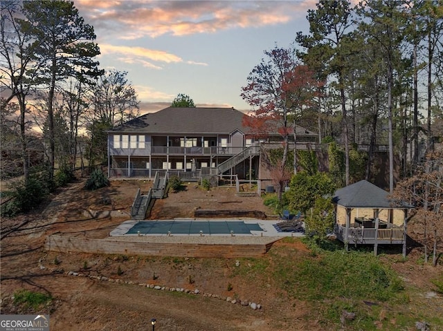 rear view of house featuring stairs and a gazebo