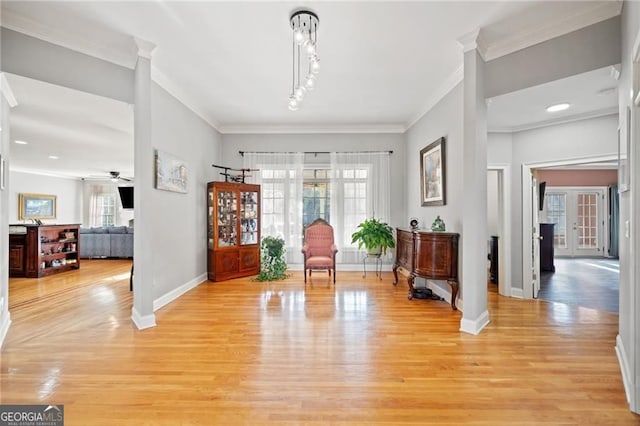 foyer entrance with baseboards, crown molding, light wood-style flooring, and a ceiling fan
