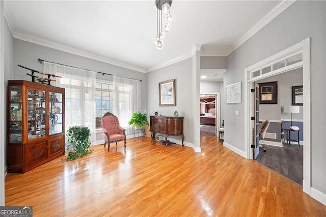 living area with light wood-type flooring, crown molding, and baseboards