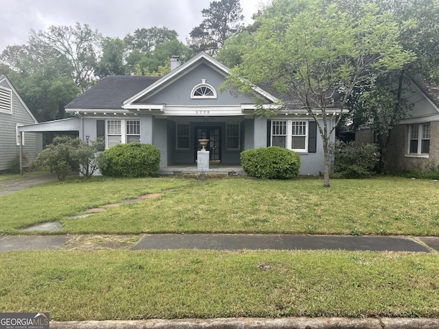 view of front of home with an attached carport, a front yard, and stucco siding