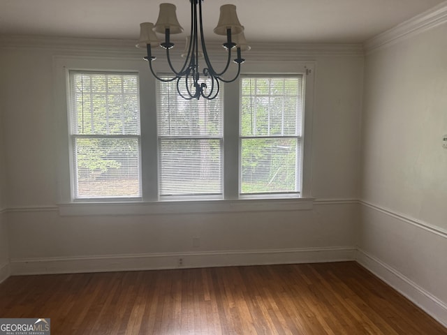 unfurnished dining area featuring ornamental molding, baseboards, a chandelier, and wood finished floors