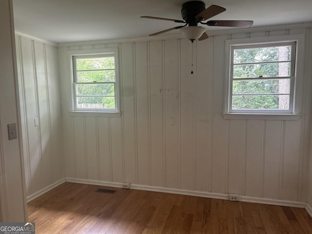 unfurnished room with baseboards, visible vents, wood finished floors, and ceiling fan