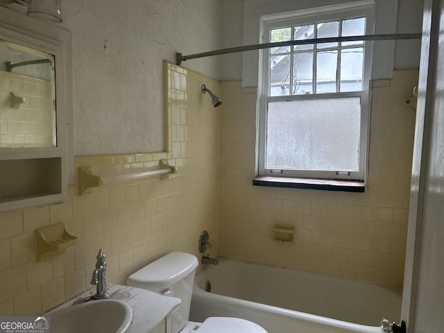 bathroom with tile walls, toilet, vanity, and shower / bathtub combination