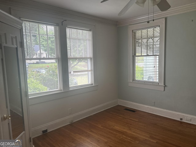 spare room with wood finished floors, ornamental molding, ceiling fan, and visible vents