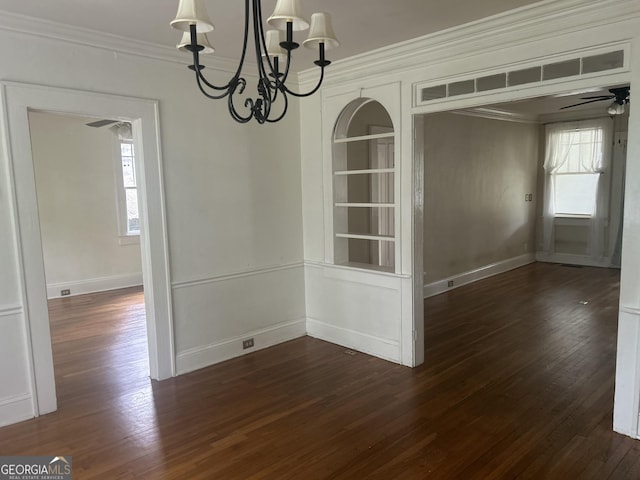 unfurnished dining area featuring crown molding, ceiling fan with notable chandelier, baseboards, dark wood-type flooring, and built in shelves